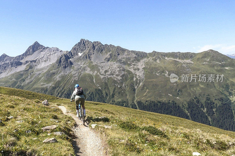 女人沿着阳光明媚的自行车道骑山地车