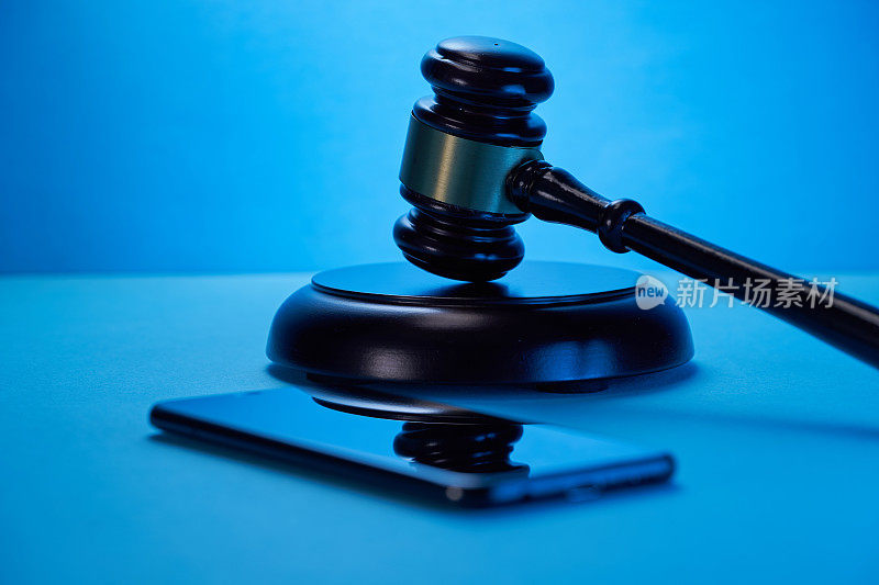 锤子槌与智能手机在蓝色的背景。正义与法律观念。