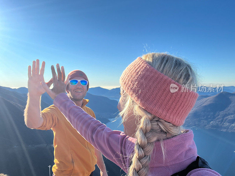 年轻的情侣在山顶上跑步，击掌