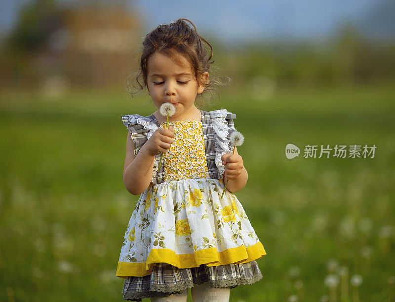 在草地上穿着黄色连衣裙的小女孩