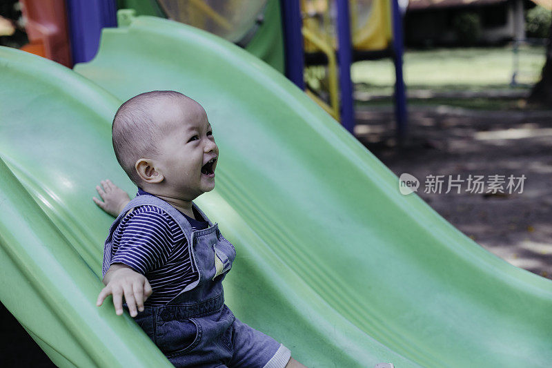 一个小男孩在操场上玩滑梯