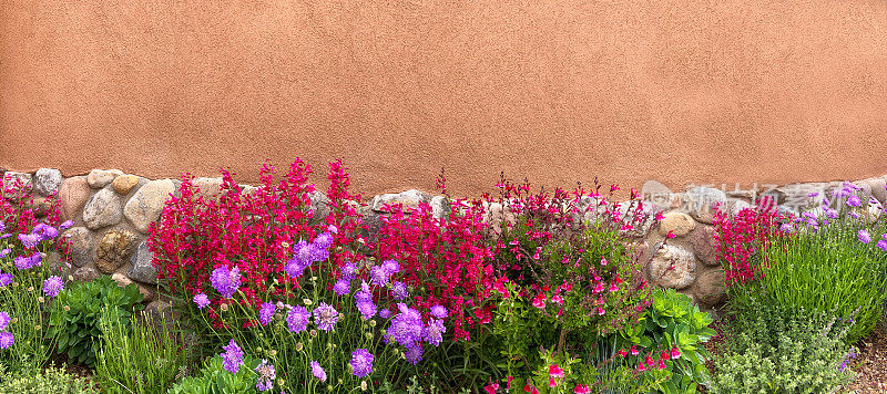 圣达菲风格:石头和土坯墙，夏天花坛广角