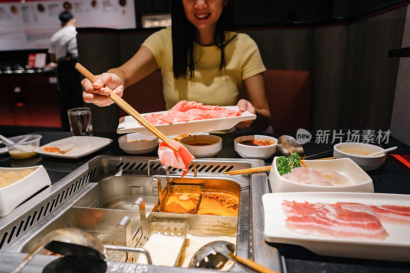 女人用火锅汤煮猪肉片