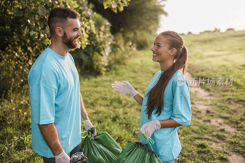 清扫日，一对年轻夫妇在森林旁的自然保护区收集垃圾。