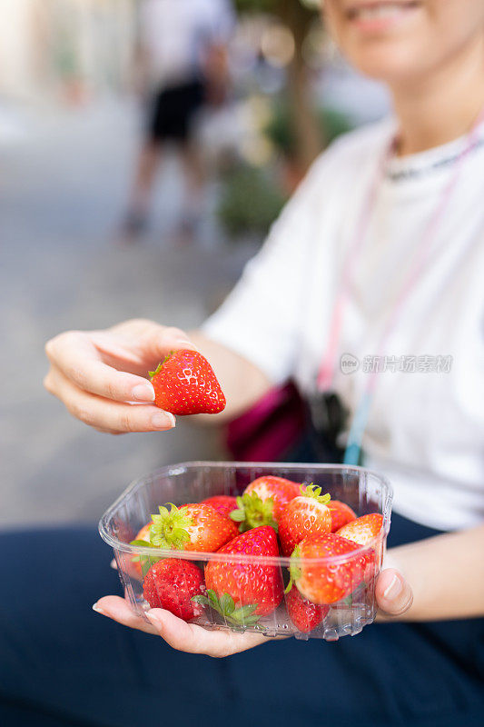 拿着一盒草莓的女人