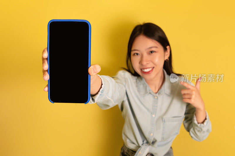 积极的亚洲女士用模型展示智能手机，宣传新的应用程序或网站，推广产品