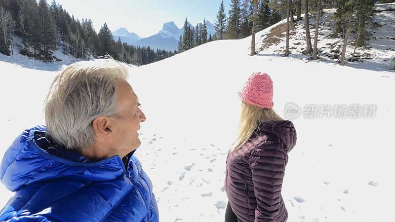 成熟的夫妇走在雪山小路上