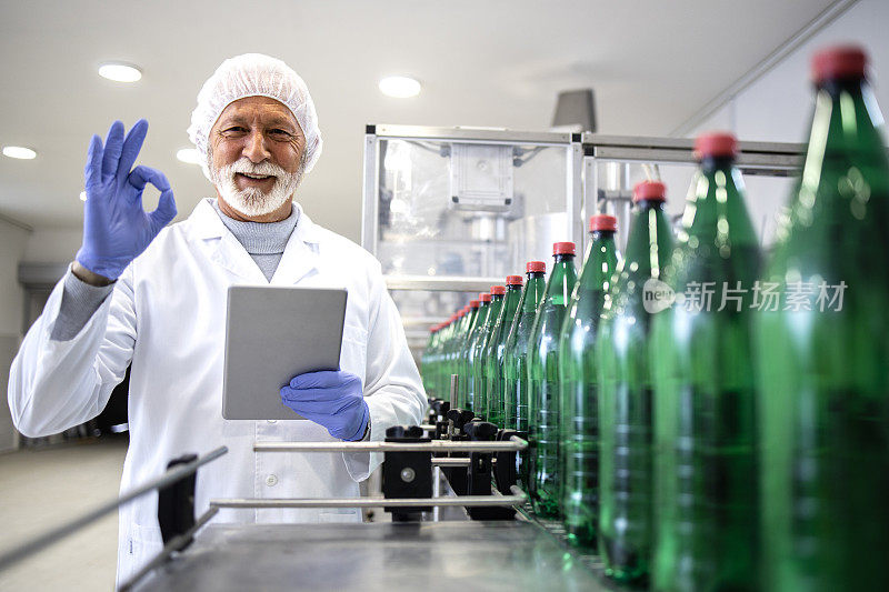 瓶装水厂技术人员为成功生产饮料持“ok”标志。