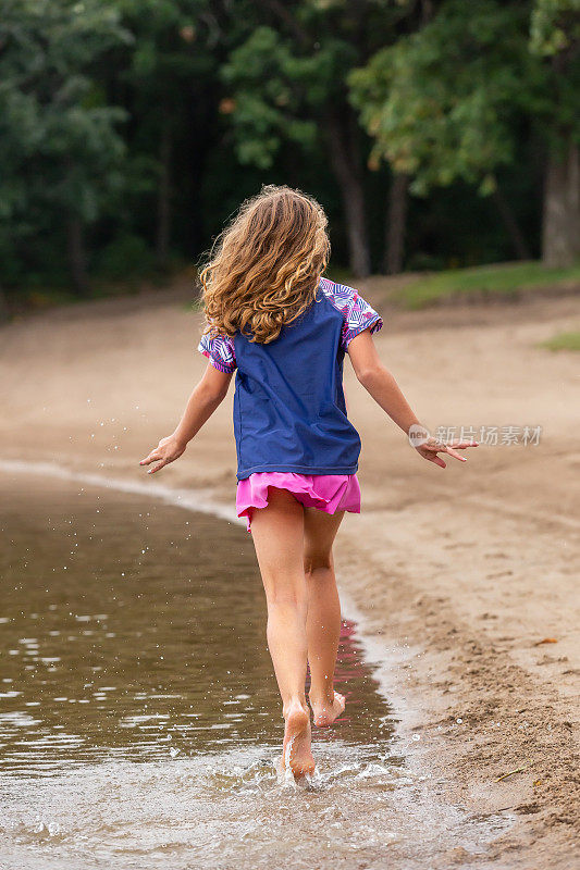 女孩在海滩的浅水中奔跑