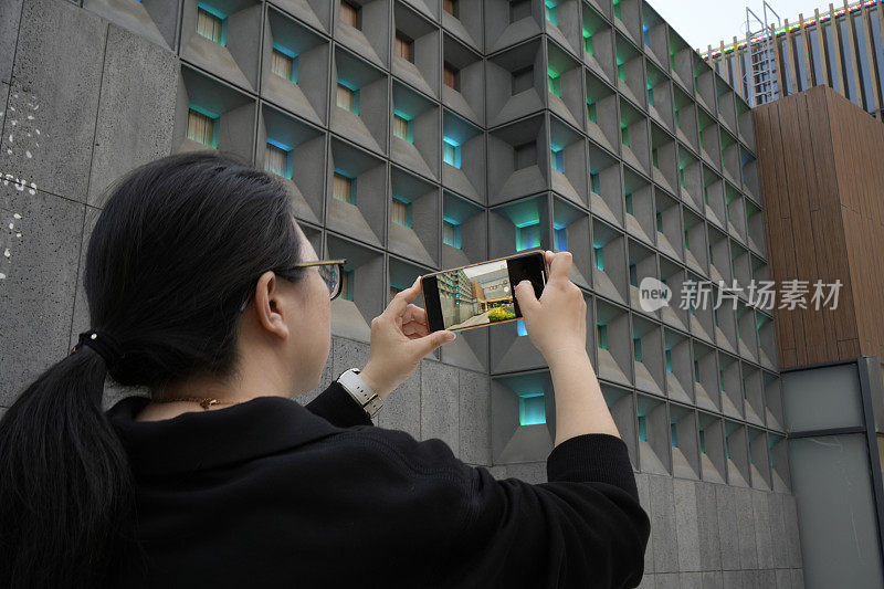 亚洲妇女用手机在户外拍摄