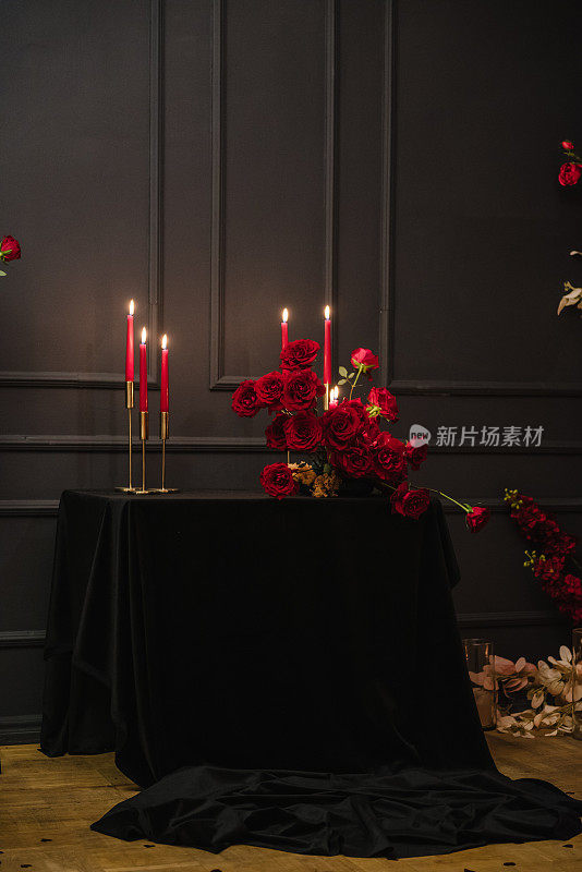 现场装饰，红色的鲜花和装饰蜡烛，惊喜求婚。为情人节情侣准备的豪华烛光餐桌。在餐厅布置餐桌。浪漫的约会。
