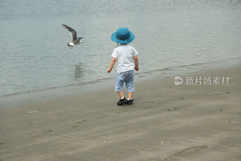 年轻的母亲带着她的小儿子在海滩上散步