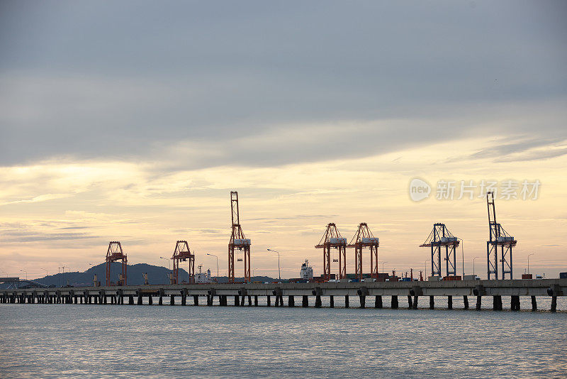 傍晚在港口、海上、河码头。工业起重机的轮廓。港口风景。明亮的夕阳，剪影动力起重机在海港，进出口的概念。