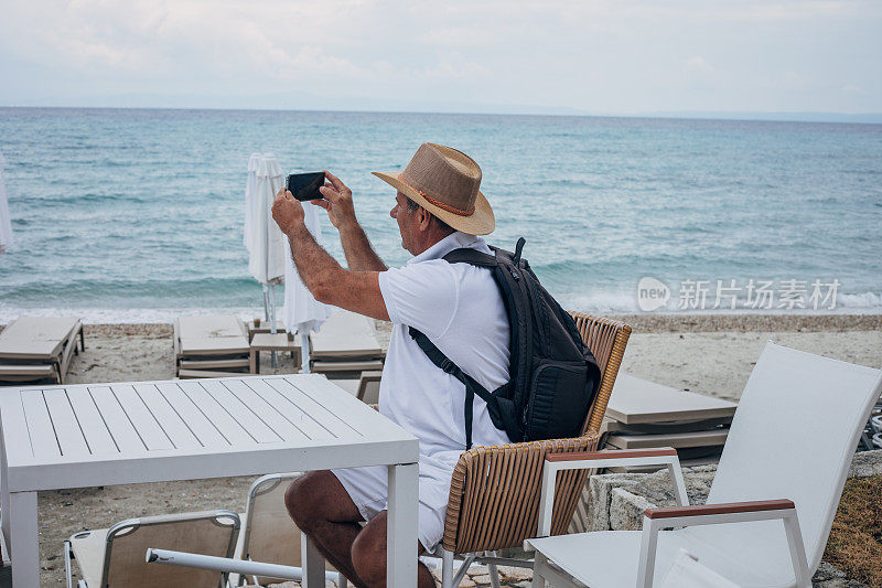 老游客在海边使用手机