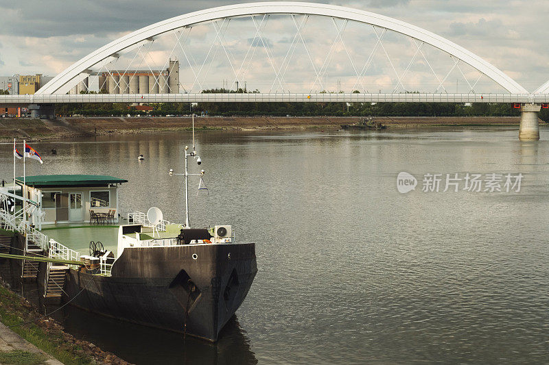 塞尔维亚诺维萨德的多瑙河上新建的铁路和运输桥，下雨天一艘饱经风雨的船