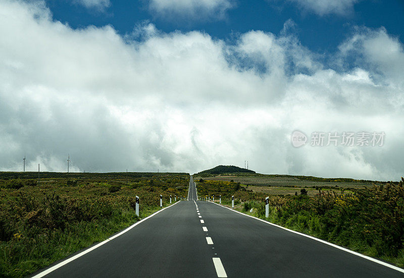 绿色的热带丘陵和高大的岩石山脉。柏油路一直延伸到地平线