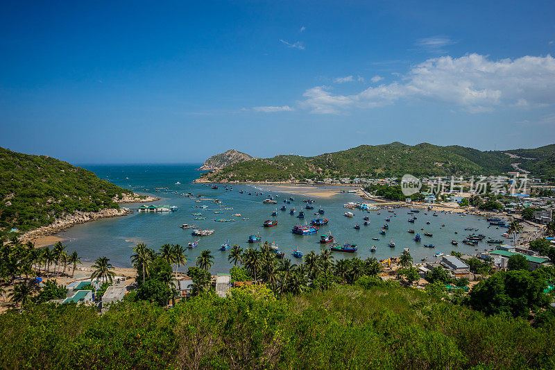 站在渔船和旅游船前，在越南宁顺清澈的蓝色海水下，紧挨着