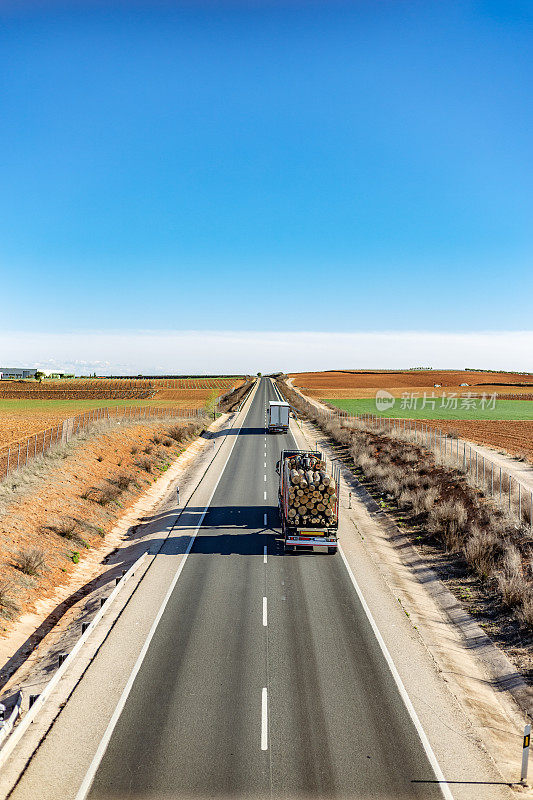 一辆在两车道国道上运输原木的卡车的高视角。