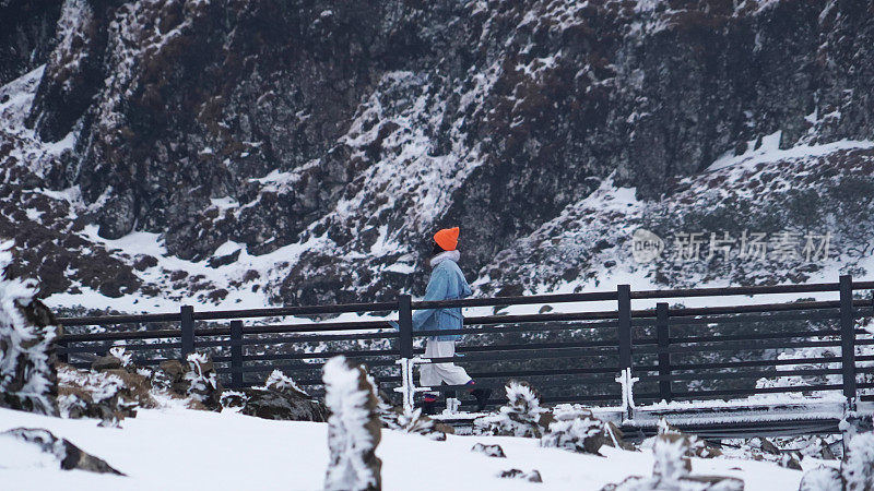 一个女人在寒冷的天气里穿行于白雪覆盖的山林之中