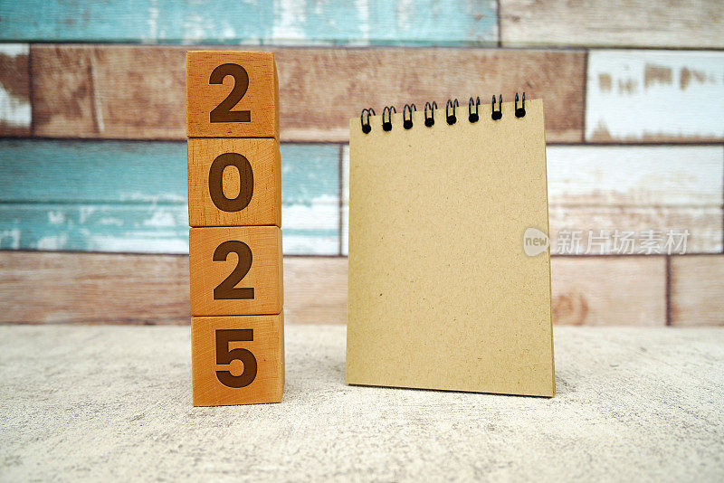 刻有2025年的木块和螺旋记事本。2025年新年快乐。