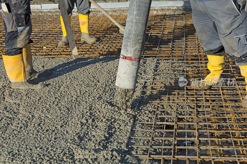 建筑工人用混凝土泵将混凝土浇筑在钢筋上