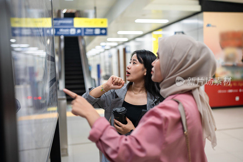 两个女上班族在火车站查看城市交通图