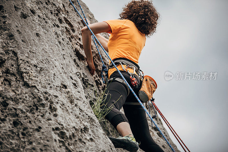 女自由攀登者正在攀登岩石山
