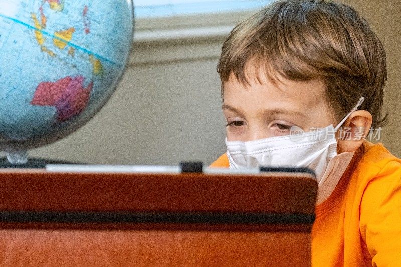 小男孩戴着防护面罩使用数码平板电脑