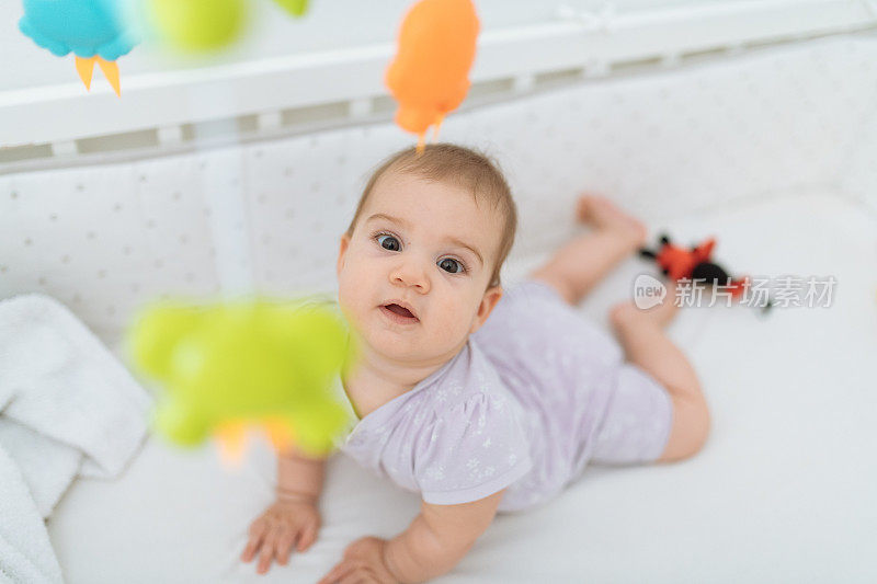6个月大的女婴看着头顶旋转的玩具
