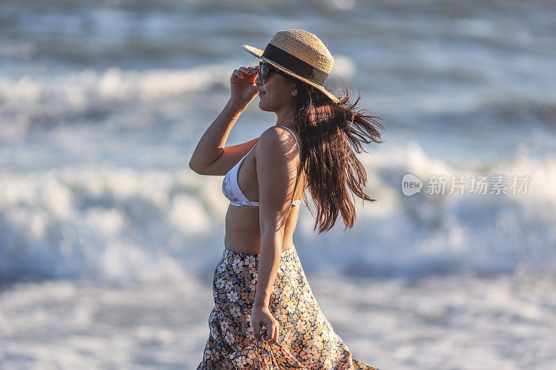 美丽的年轻女子放松在日落海滩