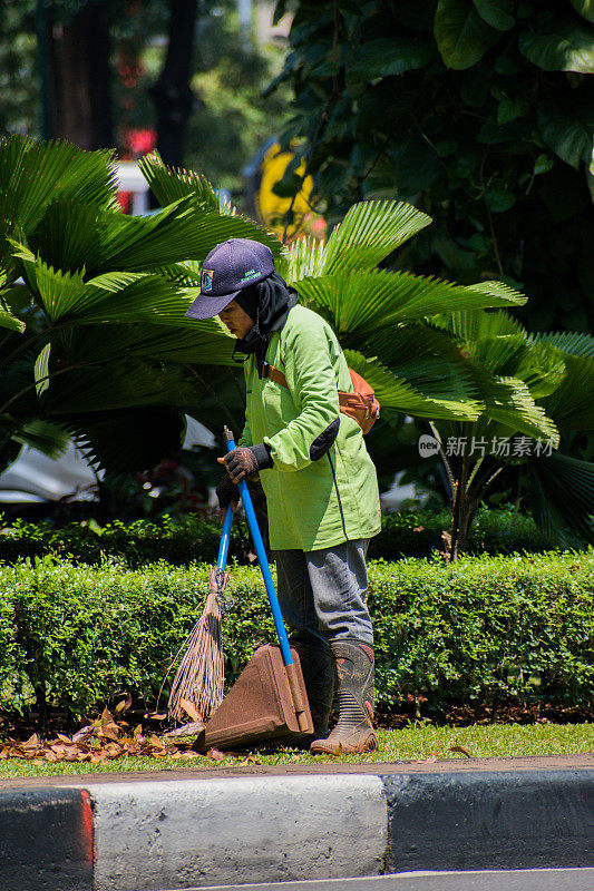 一个妇女正在清扫城市花园。