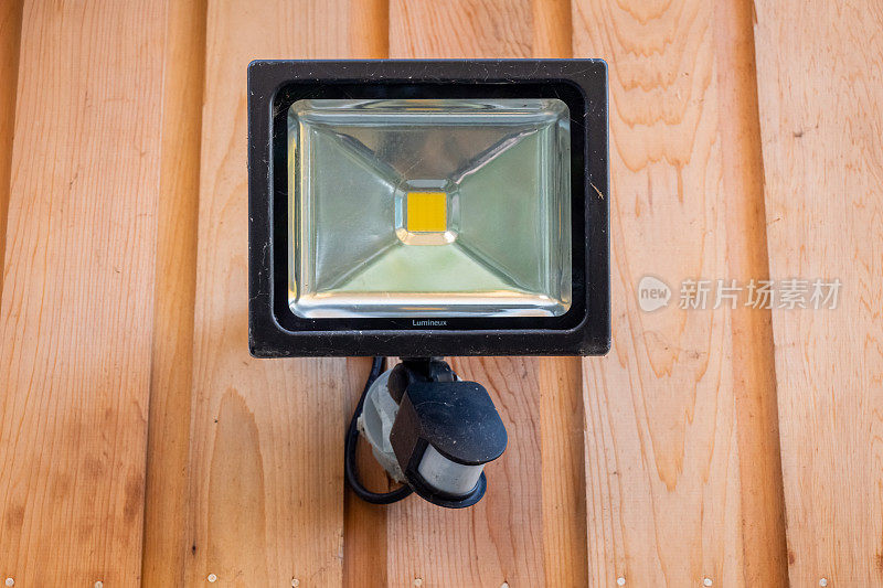 Lumineux泛光传感器灯固定在房子外面的木墙上