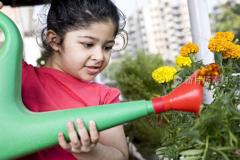 小女孩用鲜花给植物浇水
