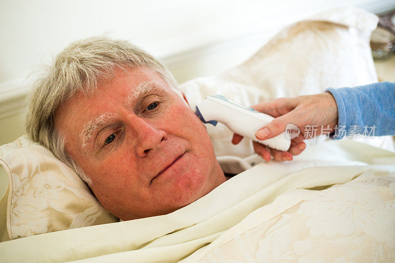 生病的老人在床上发烧，正在测量体温