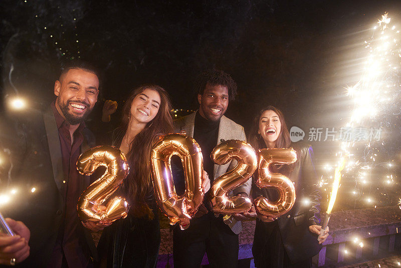 一群朋友拿着2025年的气球和烟花庆祝新年