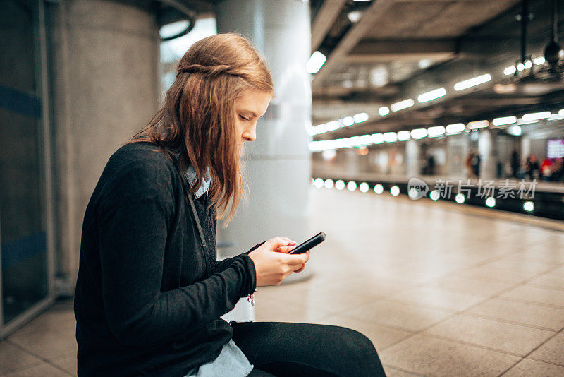 年轻的成年女子在车站发短信