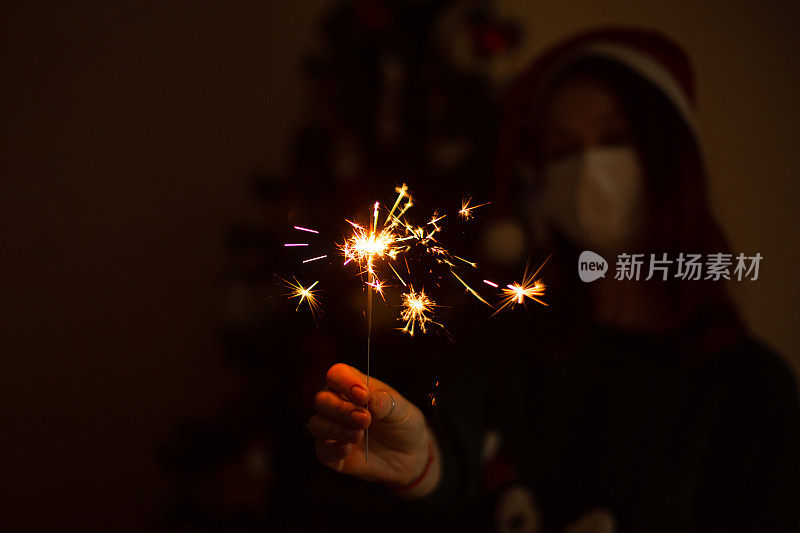 年轻女子在圣诞节或新年聚会上戴着医用面具和烟花。