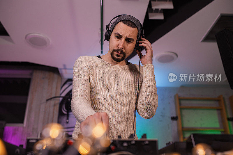 英俊的男性DJ创造和混合音乐在工作室设置