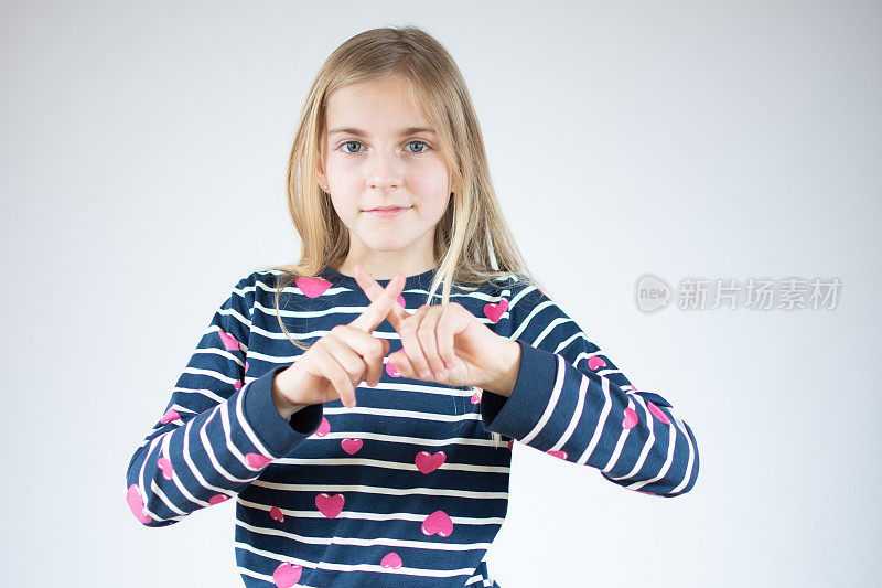 白色背景下的小女孩有拒绝的表情，交叉手指和手掌做否定的手势，愤怒的脸。