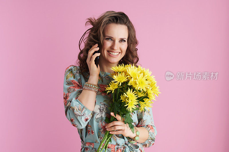 快乐的年轻女性在花裙子使用智能手机粉红色