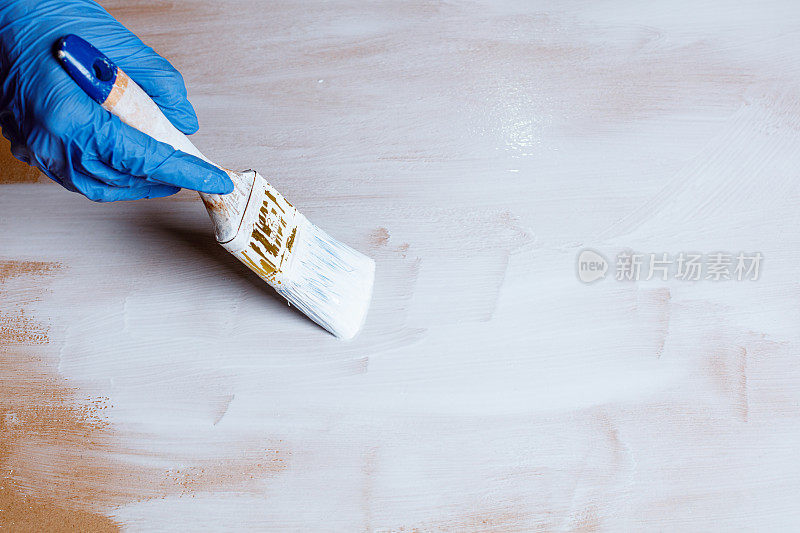 手握油漆刷，油漆木板白色