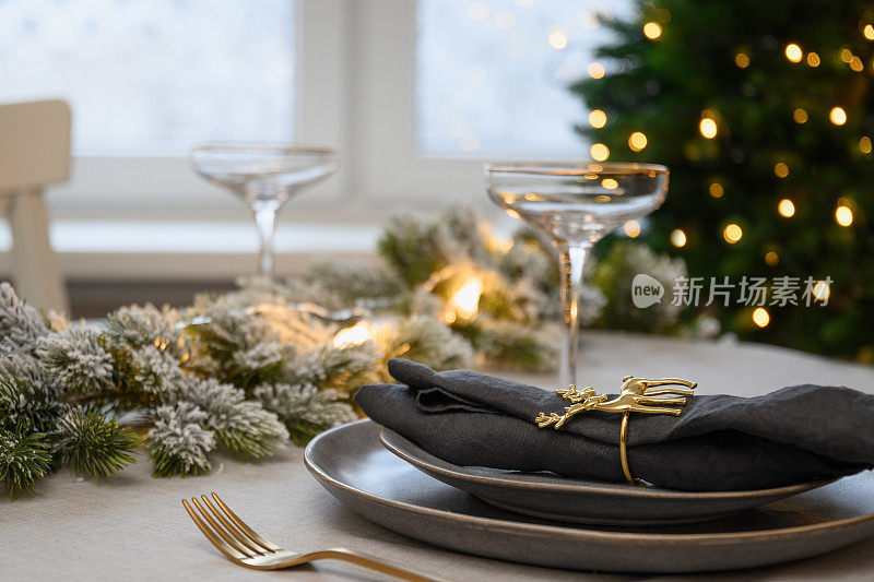 圣诞节日餐桌摆设，金色装饰，香槟。家庭节日晚餐或新年聚会。