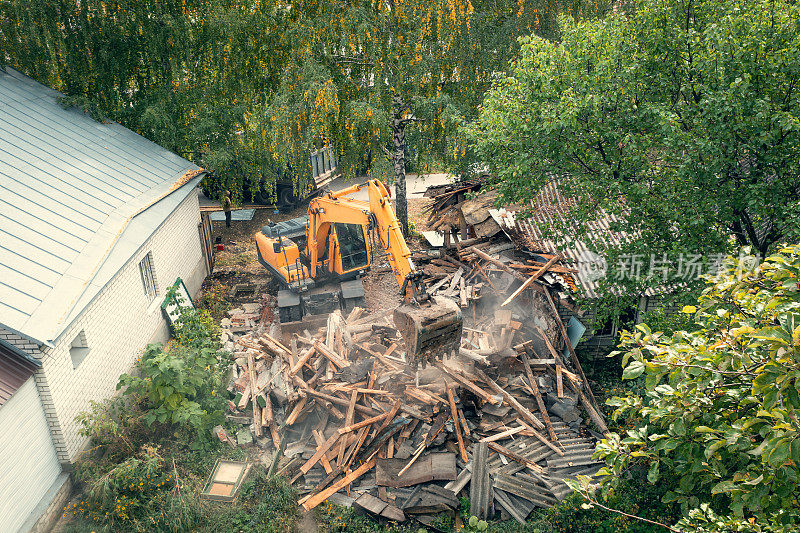 旧建筑拆除的过程。挖掘机打破房子。为新发展而拆除危房