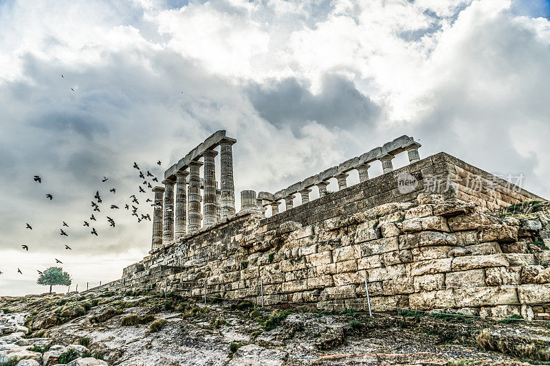 在希腊雅典的阴天里鸟群飞翔的波塞冬神庙的低角度拍摄