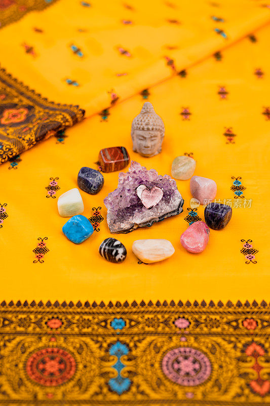 靠近一个小佛头和石英治疗石头在黄色印度教纱丽长袍背景与选择性聚焦和复制空间