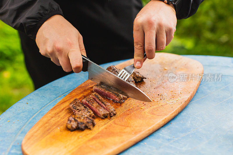 新鲜牛排。满足户外经验。晚餐在后院。红肉。准备食物的过程。小牛肉。美味的小吃。户外用餐。烤食物。用刀切肉