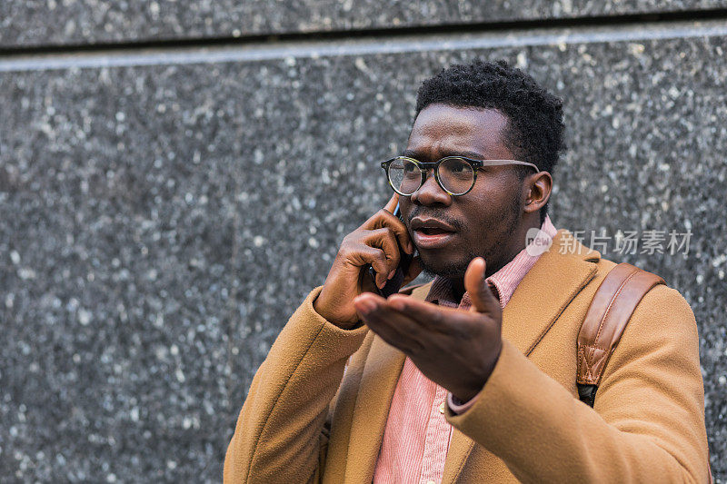 一个年轻的黑人在外面接到一个电话