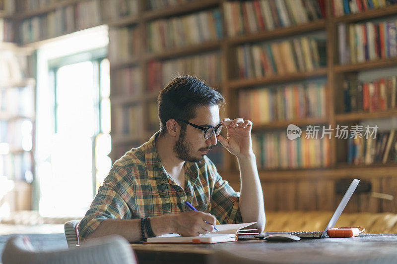 一个年轻人在图书馆用笔记本电脑学习
