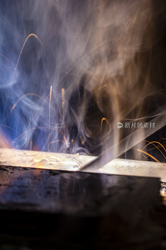 宏观焊条焊接在钢凹处，焊缝明亮，火花产生电弧产生烟雾