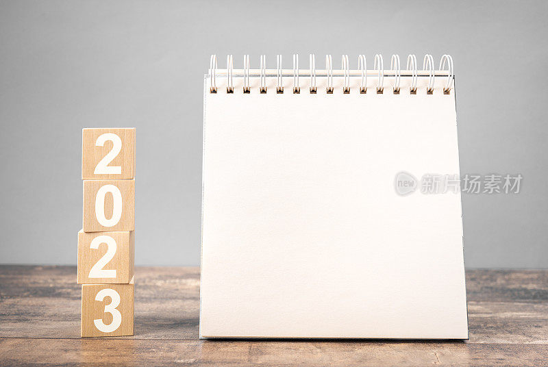 2023年模型记事本。2023立方体木桌背景。新年。2023年的计划，记事本上的文本空间，日历模型。2023年和记事本